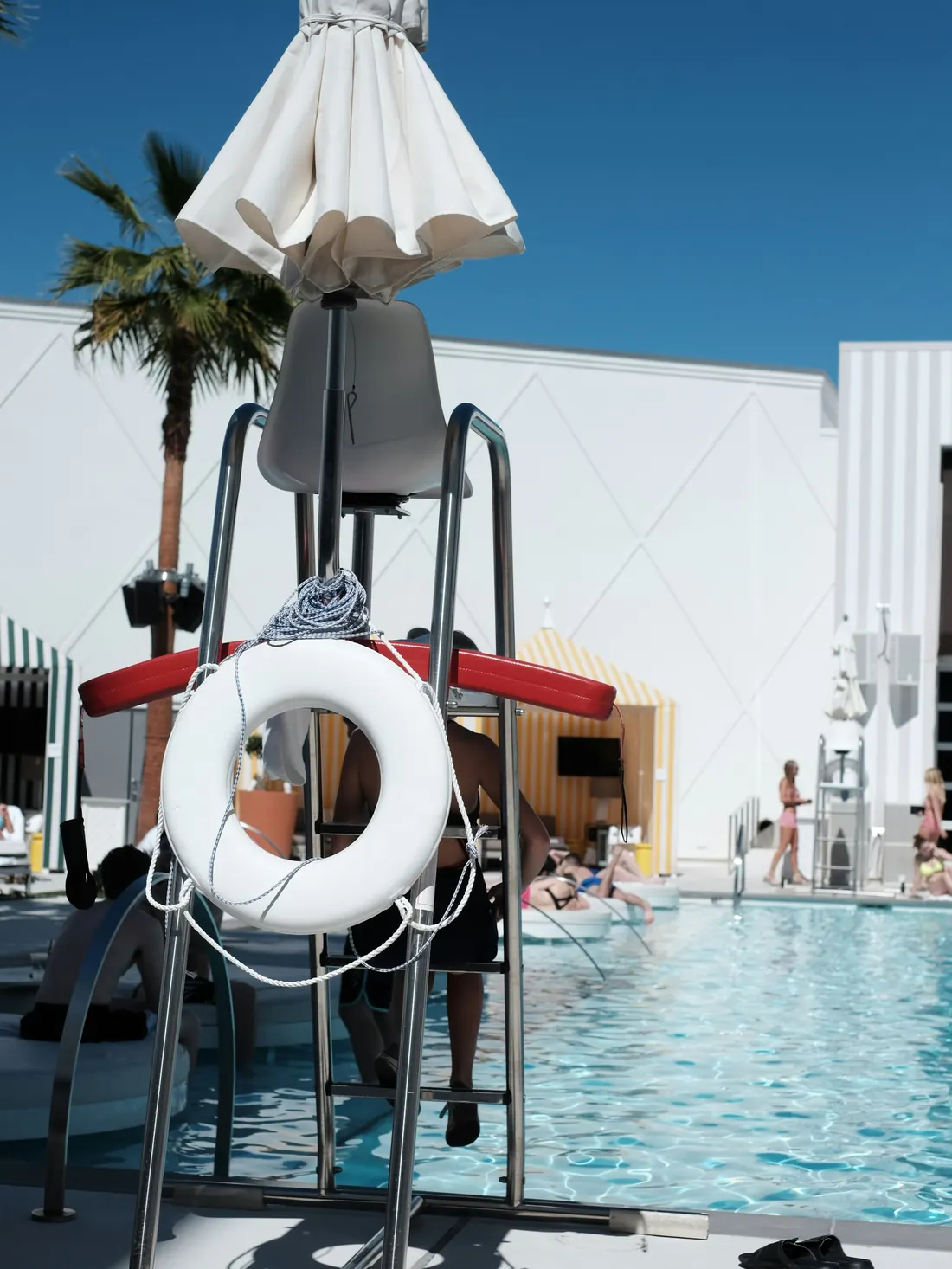 Lifeguard stand with rescue tube and ring buoy beside a resort pool