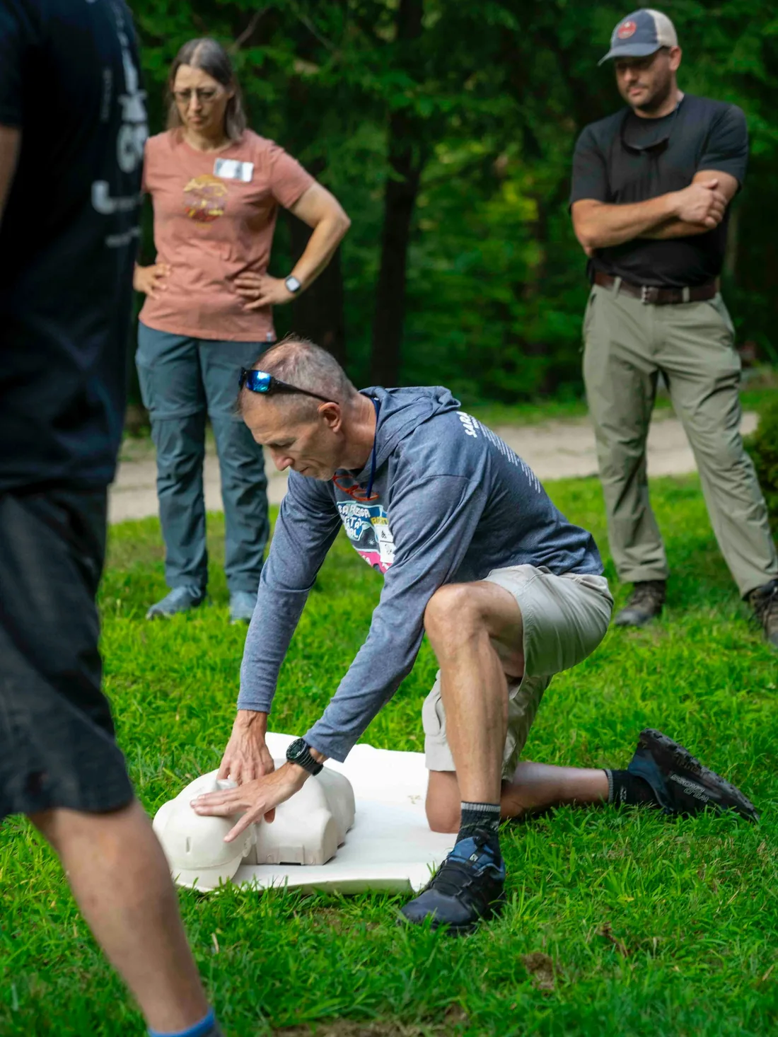 Instructor demonstrating CPR chest compressions on a training manikin to a small group