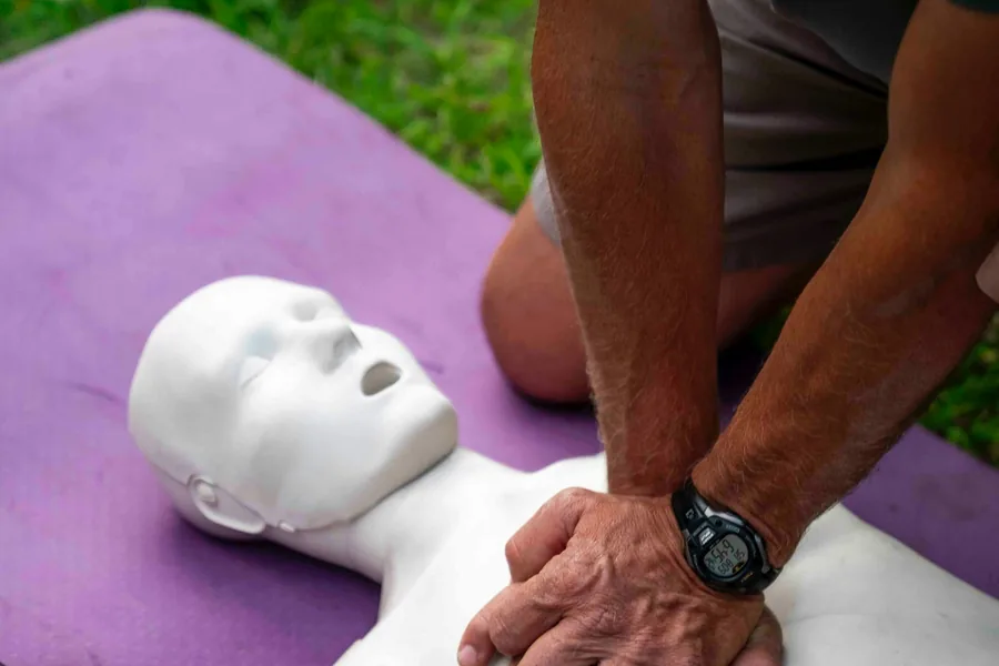 Hands performing chest compressions on a CPR training manikin