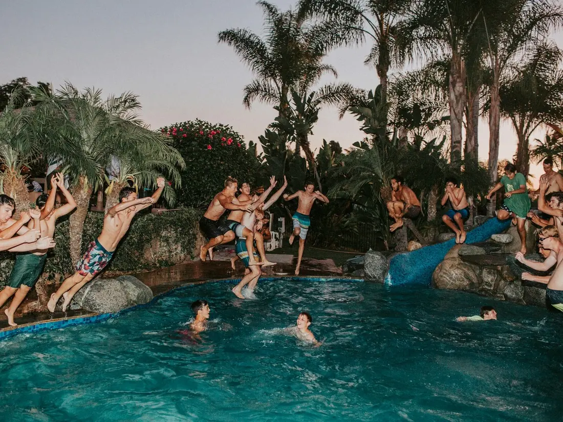 Guests jumping into a backyard pool at a private evening event