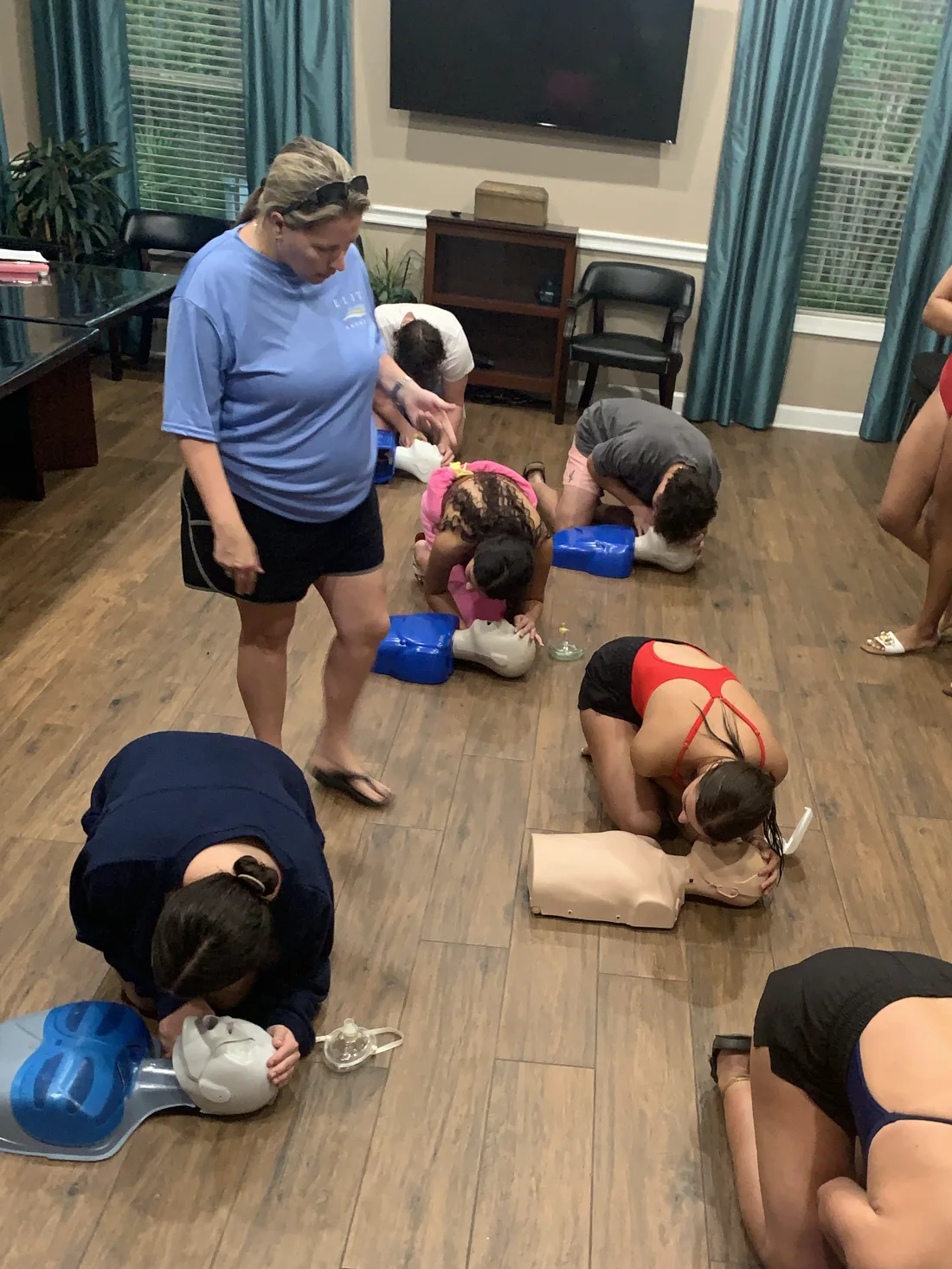 Elite instructor leading a CPR certification class as students practice compressions on training manikins