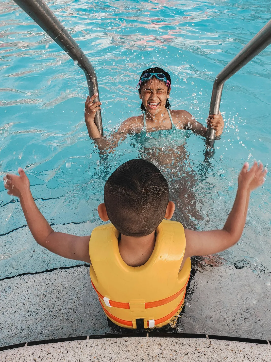Swim instructor guiding a young child wearing a life jacket in the pool